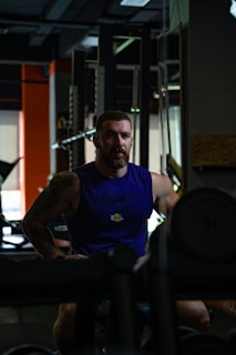 man in blue crew neck t-shirt sitting on black bench press