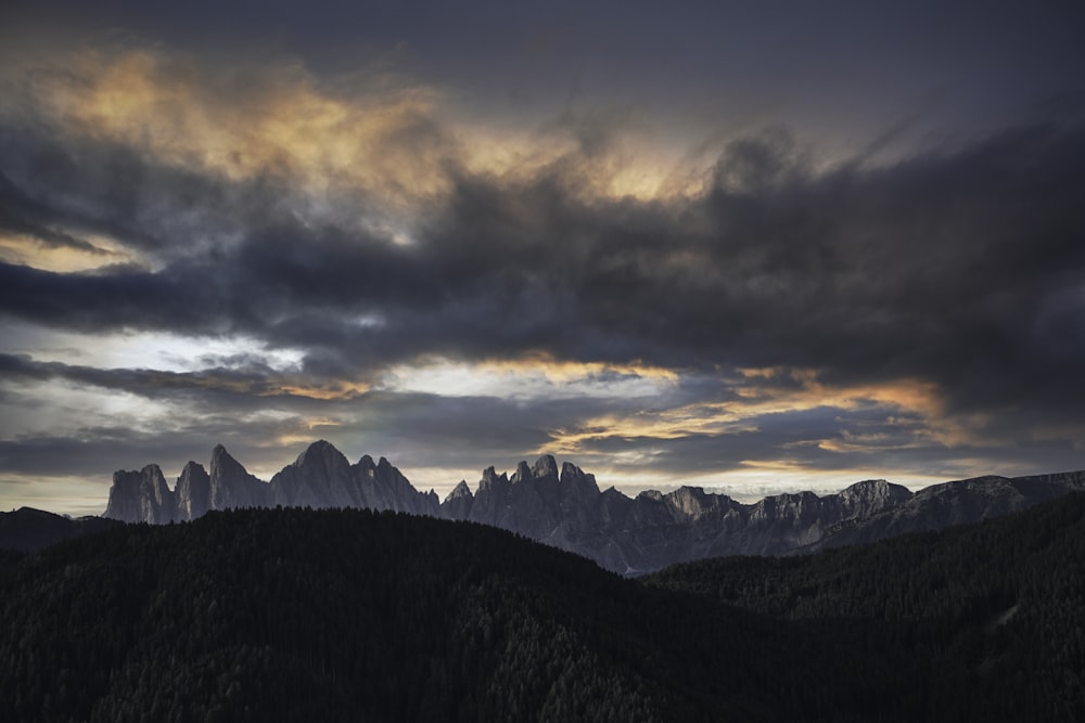 green trees on mountain under cloudy sky during daytime