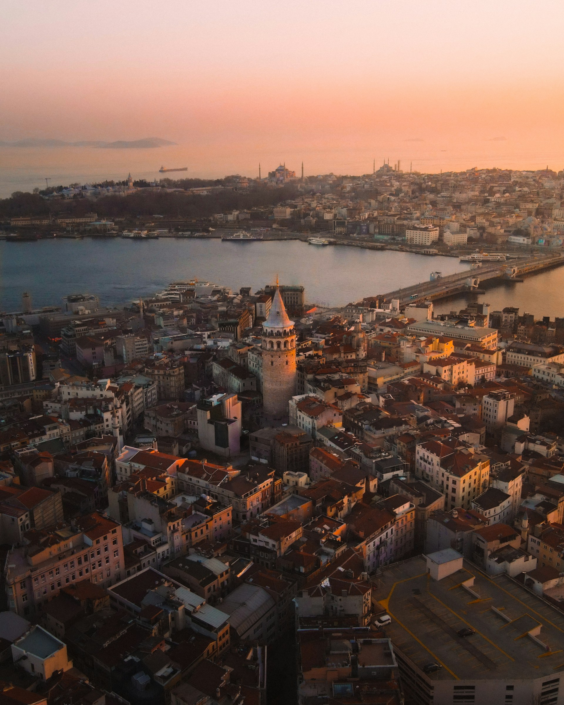 A dynamic drone view over an urban landscape in England, showing the contrast between historic buildings and modern architecture under a soft sunset.