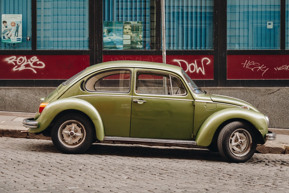 green classic car parked beside red and white building