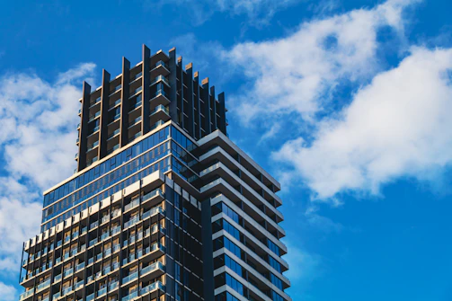 Modern commercial building with glass facade under blue sky.