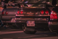 A lineup of Nissan Skyline GT-R models (R32, R33, R34) showcasing various aftermarket parts in a garage setting.