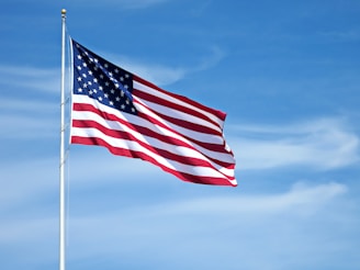 us a flag on flag pole under blue sky during daytime