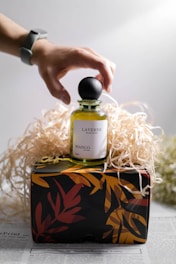 person holding gold and black perfume bottle
