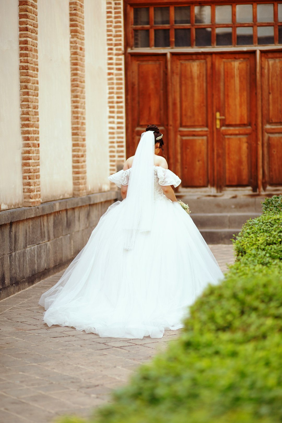 woman in white wedding dress walking on sidewalk during daytime