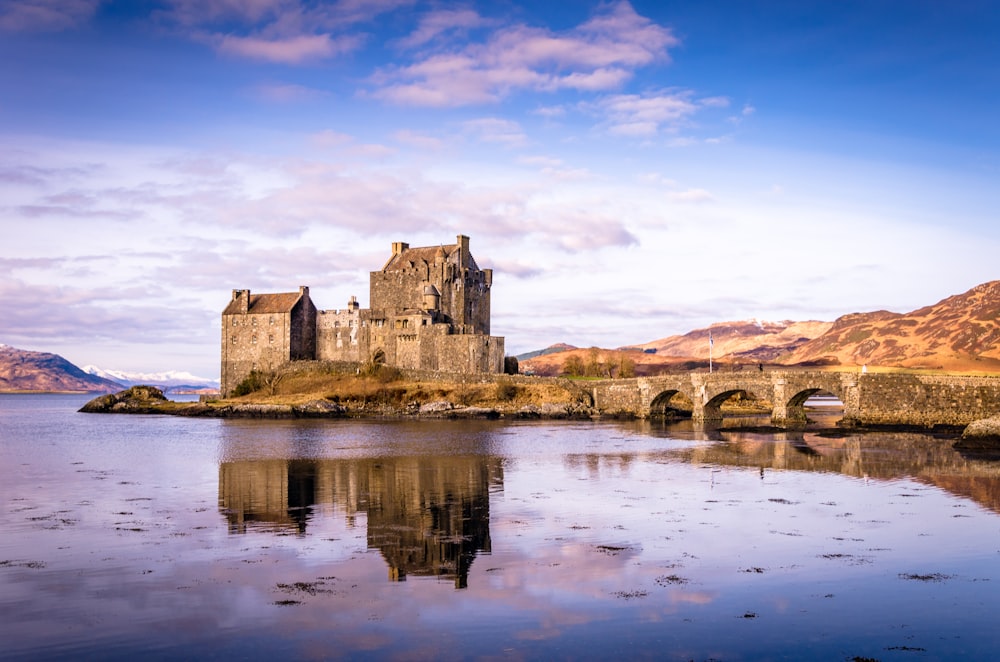 a castle sitting on top of a lake next to a bridge