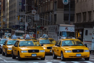 yellow taxi cab on road near white concrete building during daytime