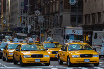 yellow taxi cab on road near white concrete building during daytime