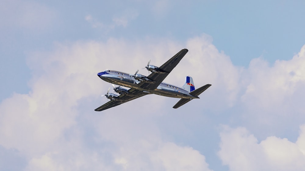 white and blue airplane in mid air during daytime