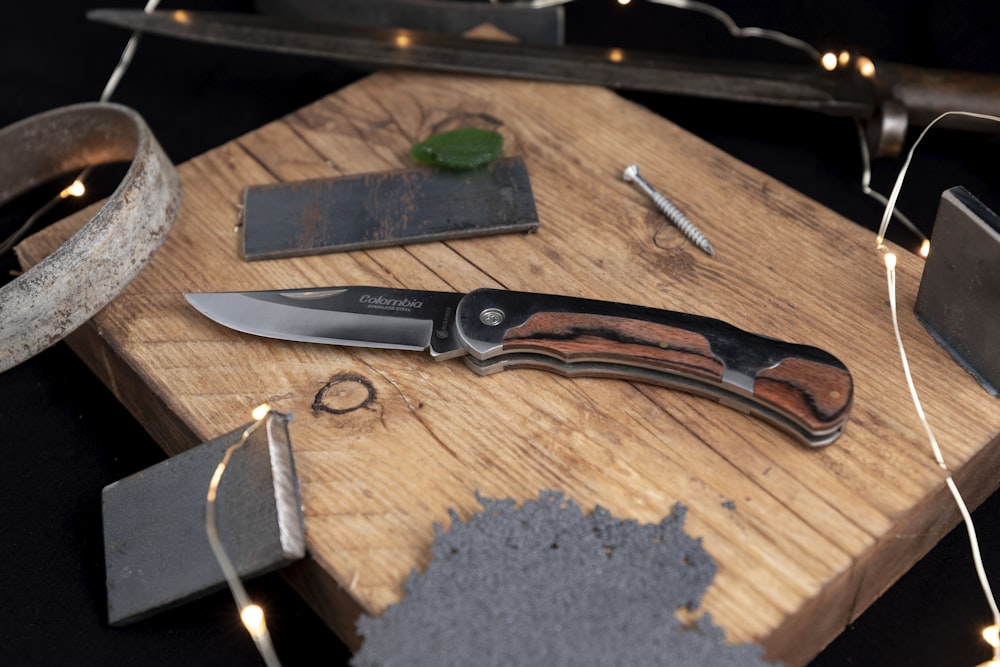 coltello con manico nero e marrone su tavolo di legno marrone