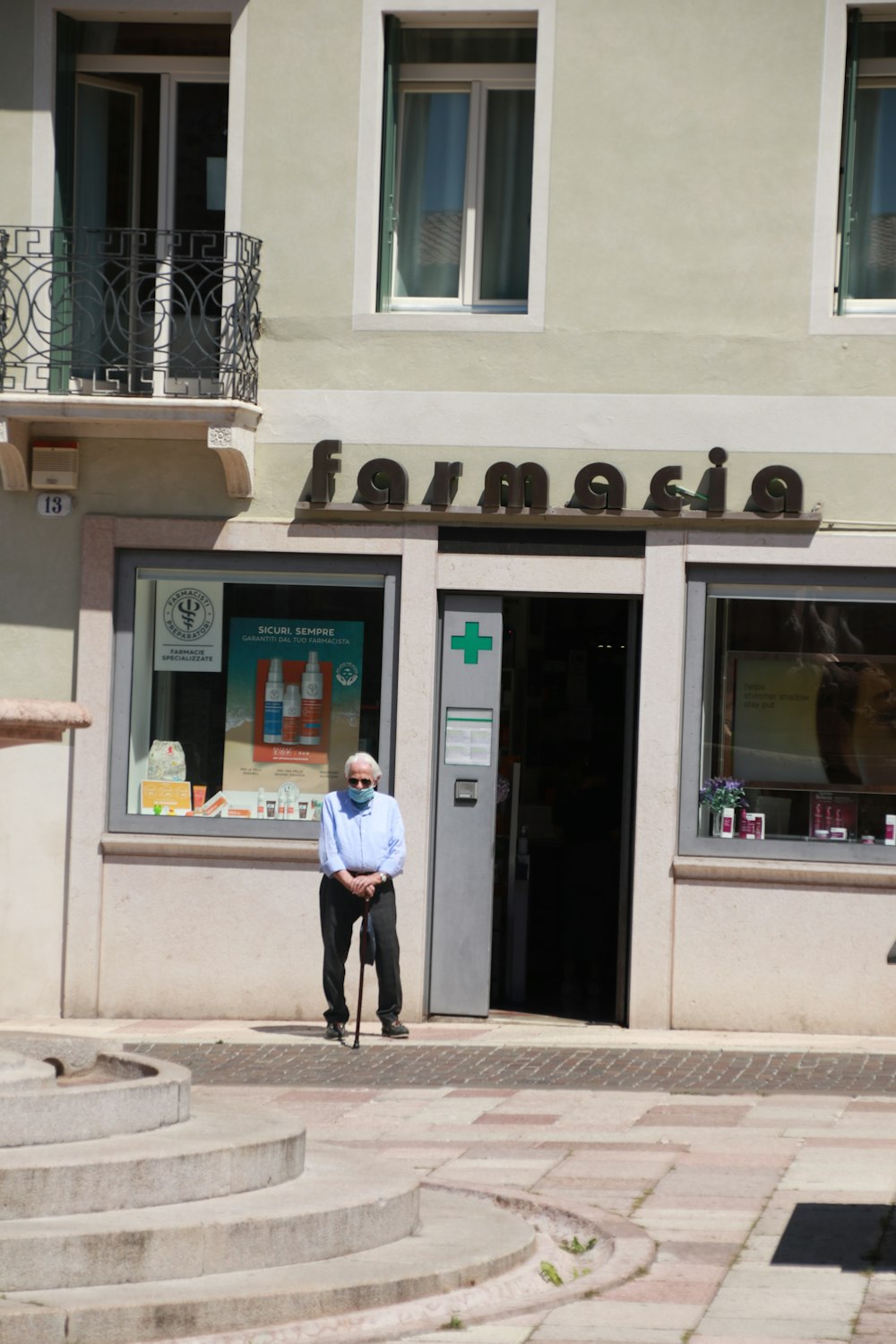 homem na camisa social branca e calças pretas em pé na frente da loja