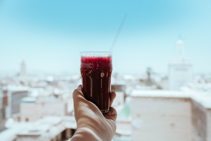 Hand raising a glass of fresh beet juice to the sky
