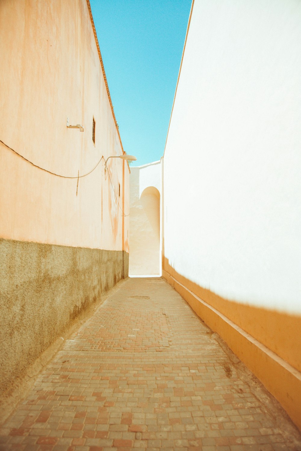 brown wooden pathway between white wall