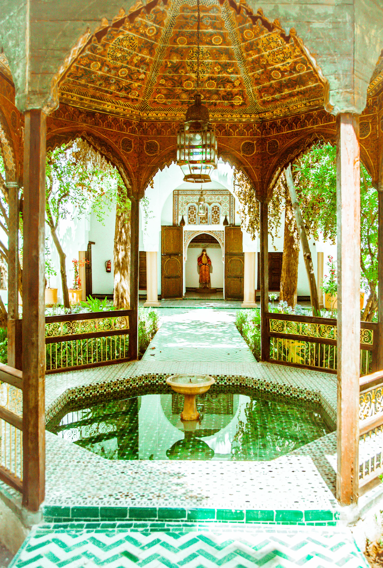 A traditional riad courtyard with a fountain, lit for the evening