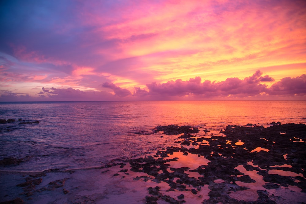 body of water under cloudy sky during sunset