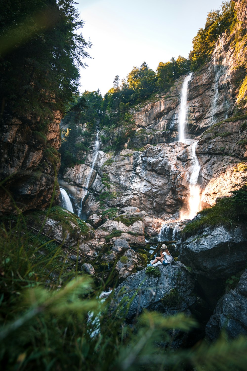 person in black jacket standing on rock near waterfalls during daytime