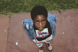 boy in blue denim jacket standing on brown concrete floor