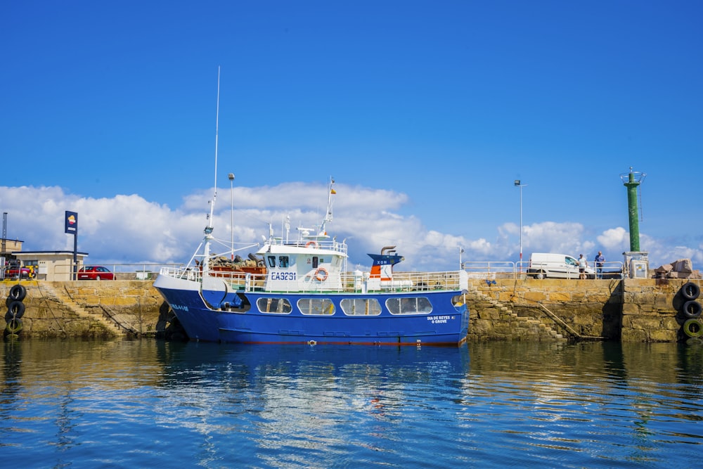 blau-weißes Boot tagsüber auf einem Gewässer unter blauem Himmel