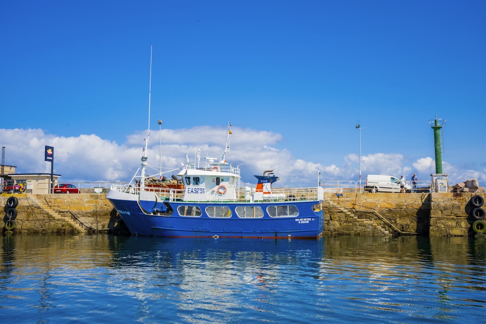 blue and white boat on body of water under blue sky during daytime