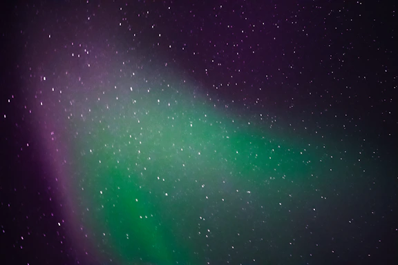 A serene night sky illuminated by vibrant northern lights in shades of blue and cyan.