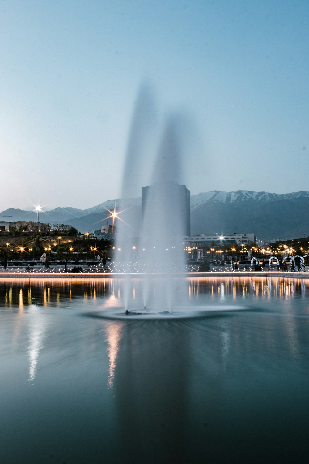 water fountain near city buildings during night time