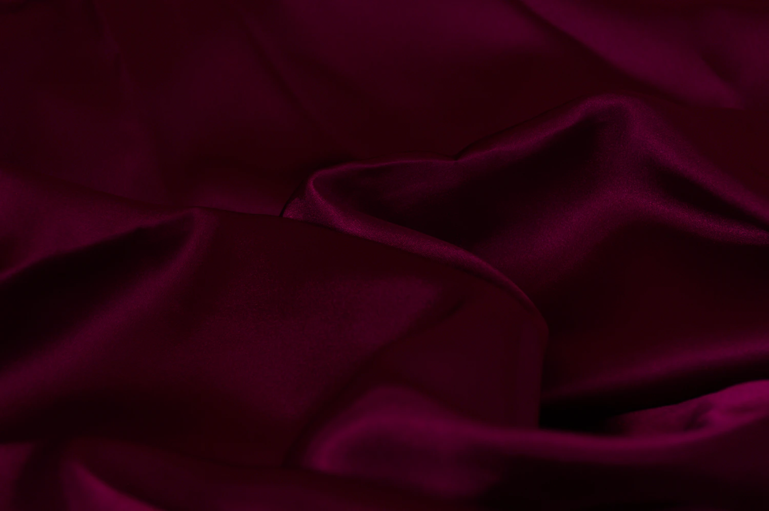 Oxblood silk pooled and lit from one side, cropped to a band