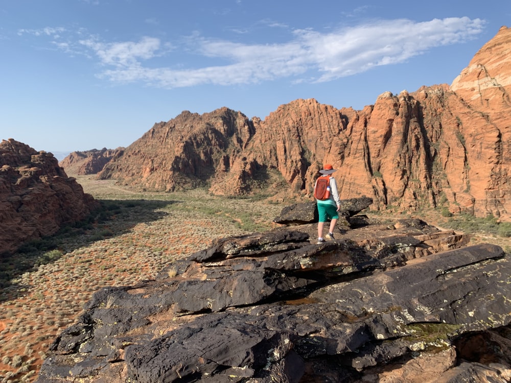 Frau in türkisfarbenem Tanktop und blauen Jeans steht tagsüber auf dem Rocky Mountain