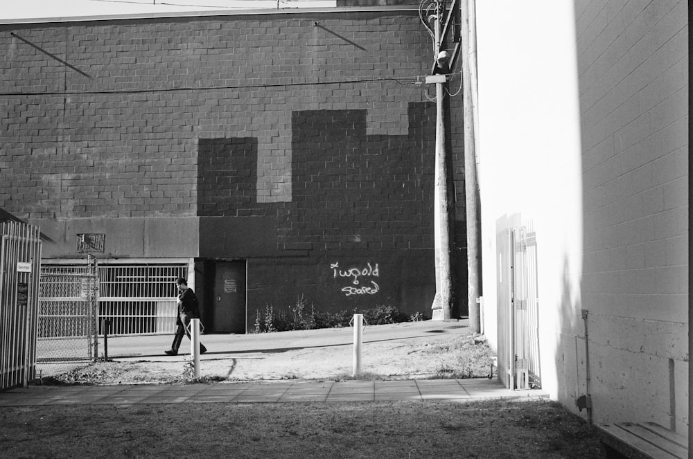 grayscale photo of 2 men walking on sidewalk near building