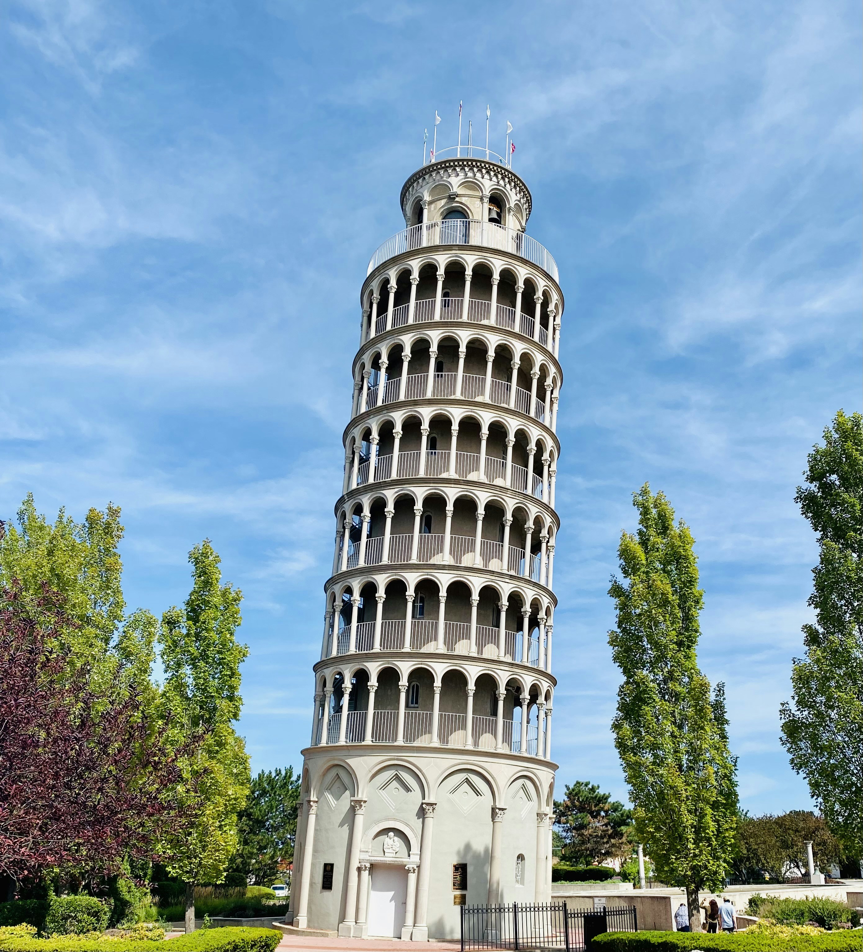 white concrete tower near green trees under blue sky during daytime