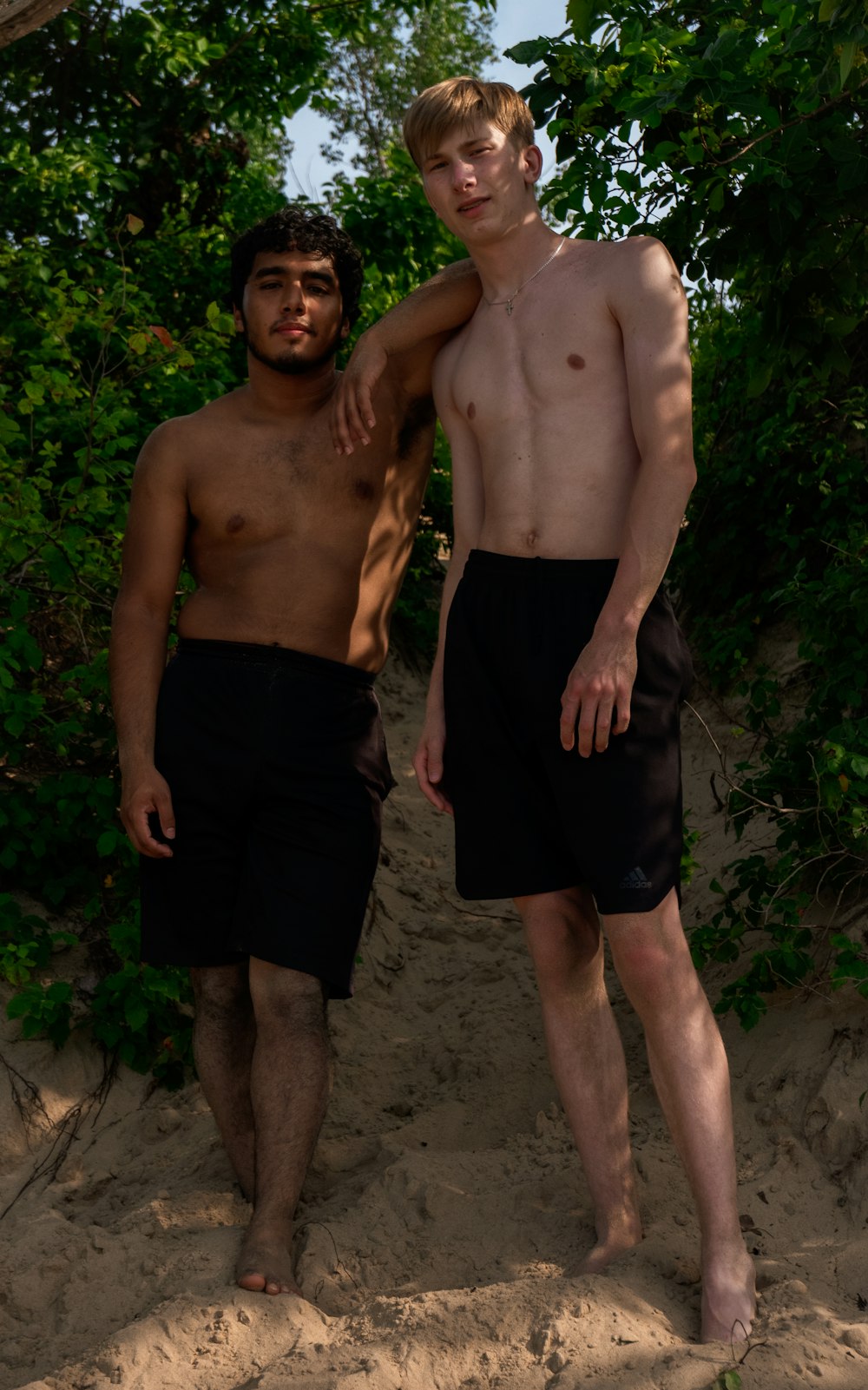 2 men in black shorts standing on green grass field during daytime