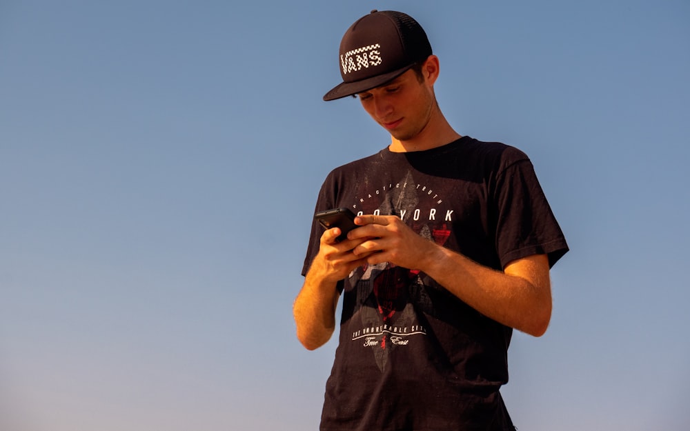 man in black crew neck t-shirt wearing black cap