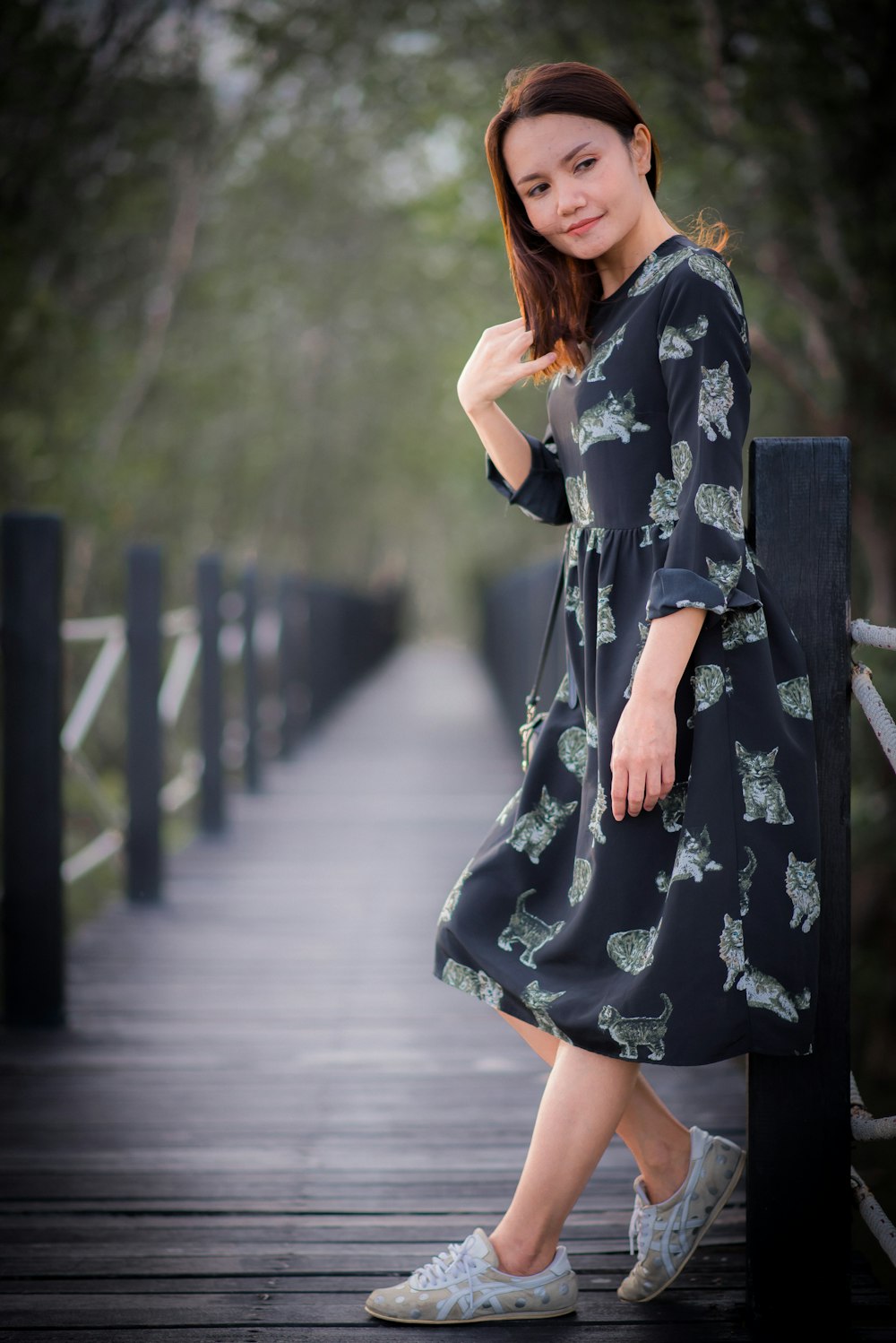 woman in black and white floral dress standing on gray concrete pathway during daytime