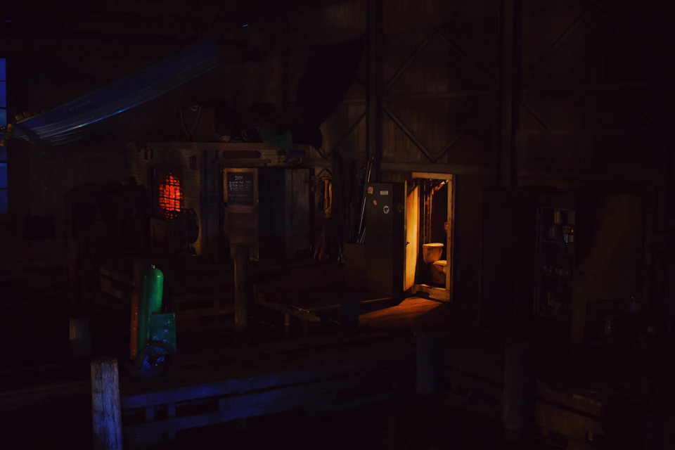 Dimly lit room with open metal door on right side, surrounded by scattered objects