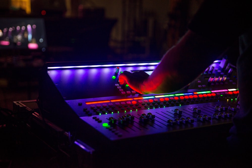 person playing audio mixer with blue and red lights
