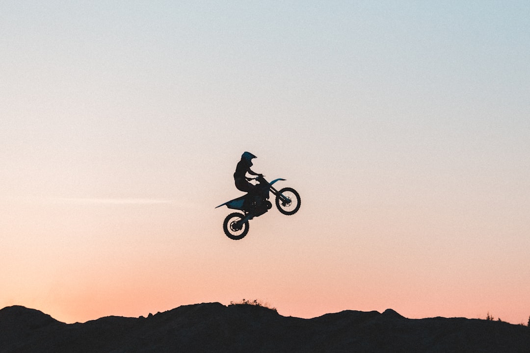 silhouette of man riding bicycle on mid air during daytime