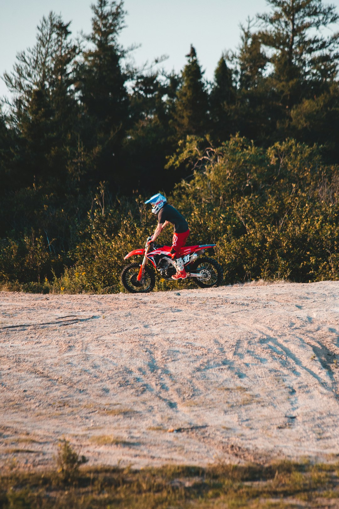 man in blue and red motocross suit riding motocross dirt bike on brown dirt road during