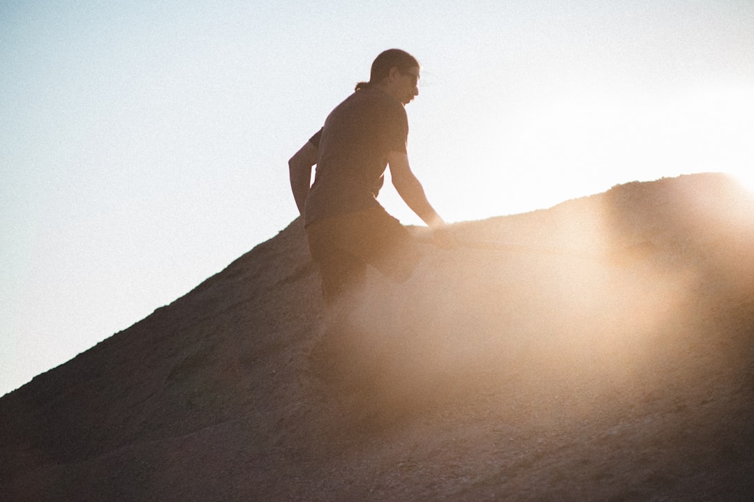 man in black shorts sitting on brown sand during daytime