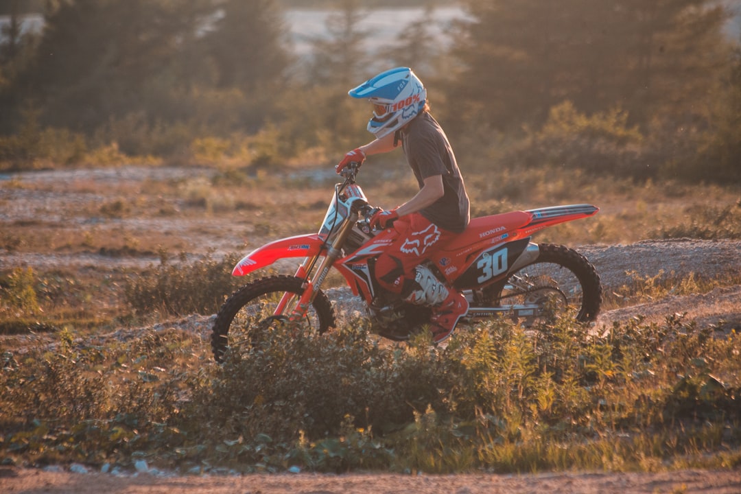 man in blue jacket riding red dirt bike