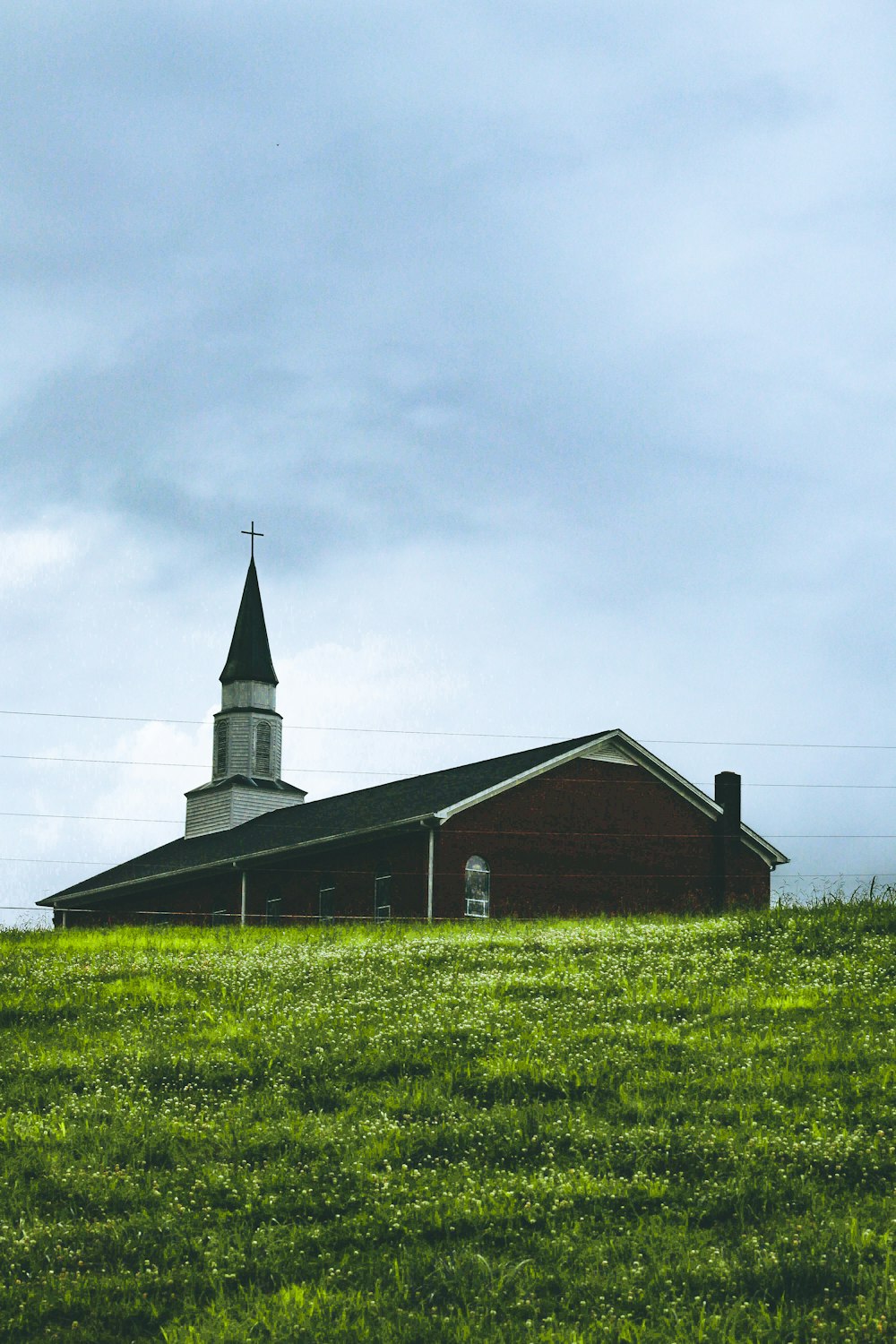 brown and black wooden house on green grass field under white clouds during daytime