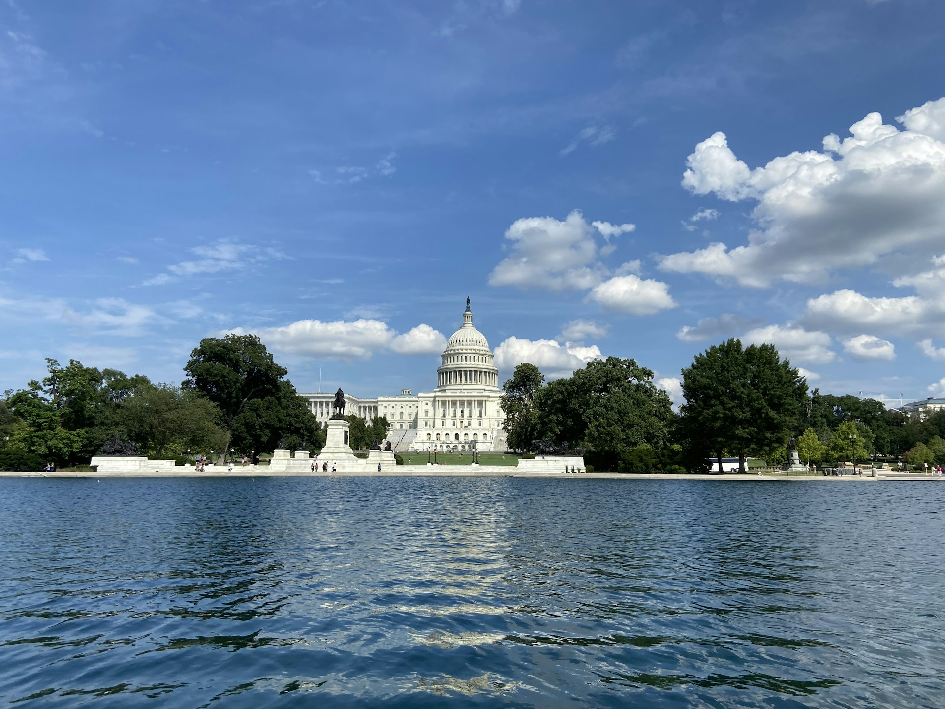 white concrete building near body of water under blue sky and white clouds during daytime