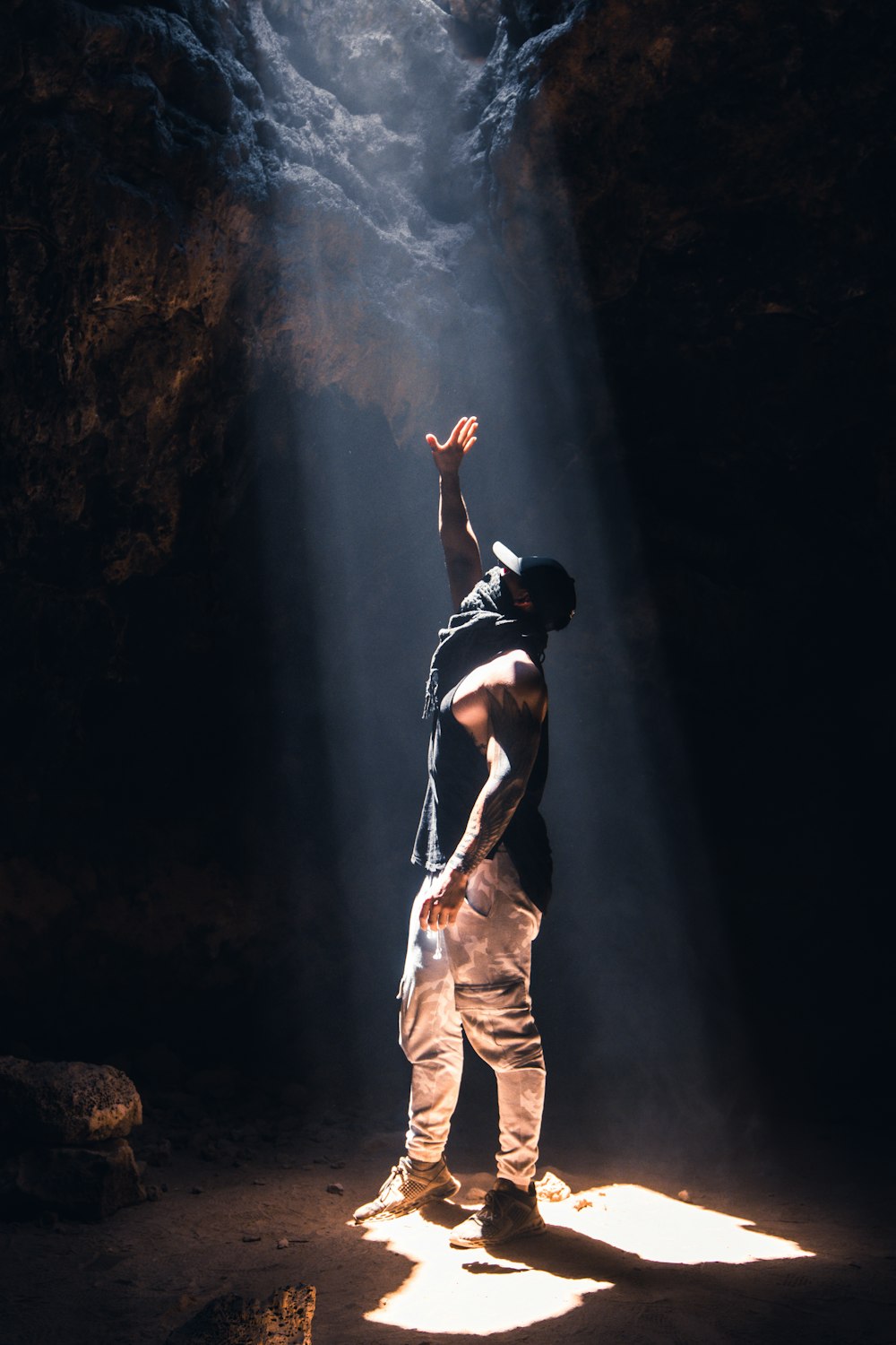 uomo in canotta nera e pantaloni beige in piedi sulla roccia
