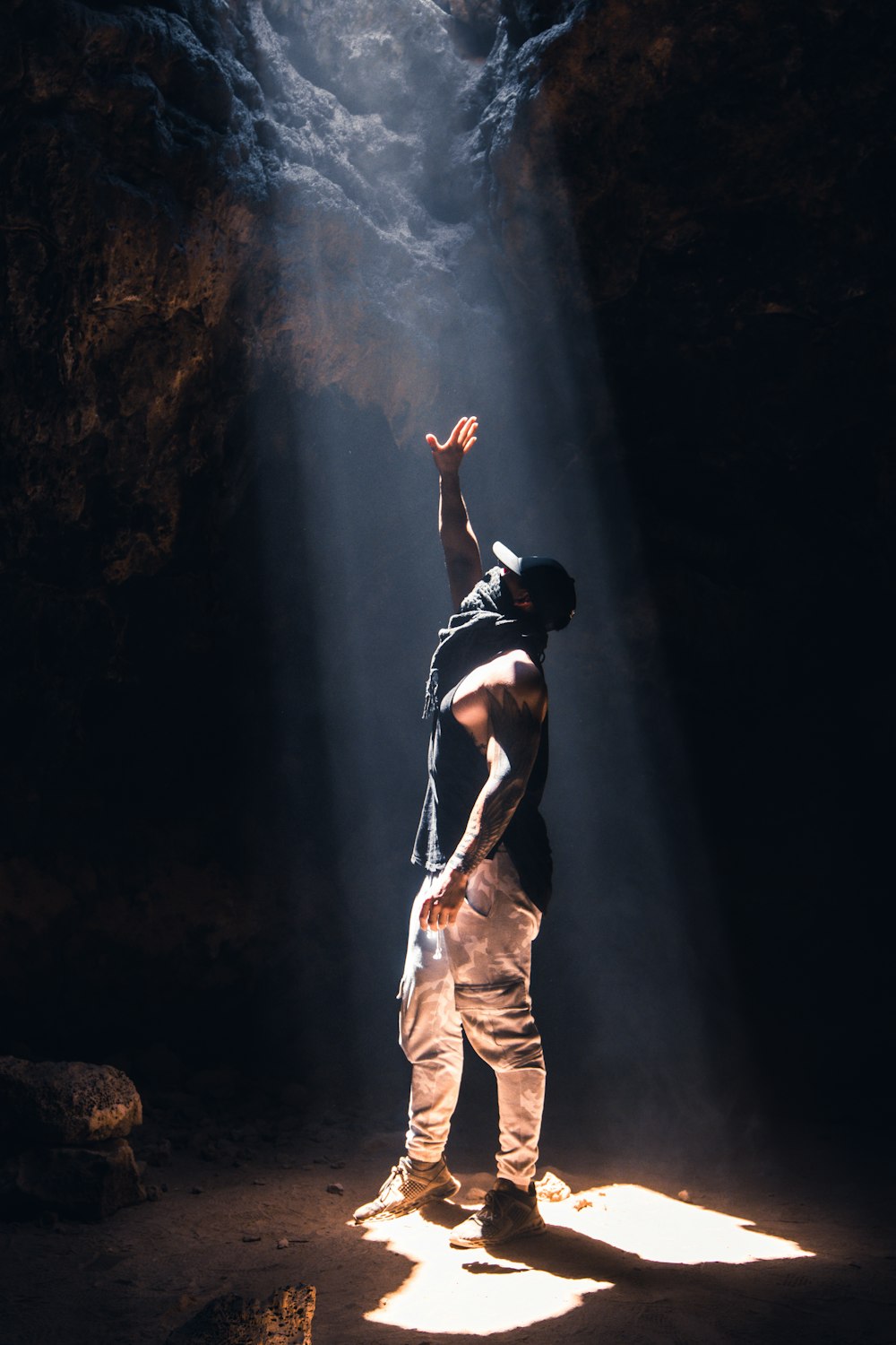 Mann in schwarzem Tanktop und beiger Hose auf Felsen stehend