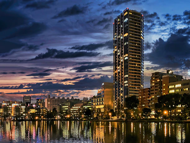 Editorial-style shot of a modern city skyline at dusk with glass reflections and deep purple hues.