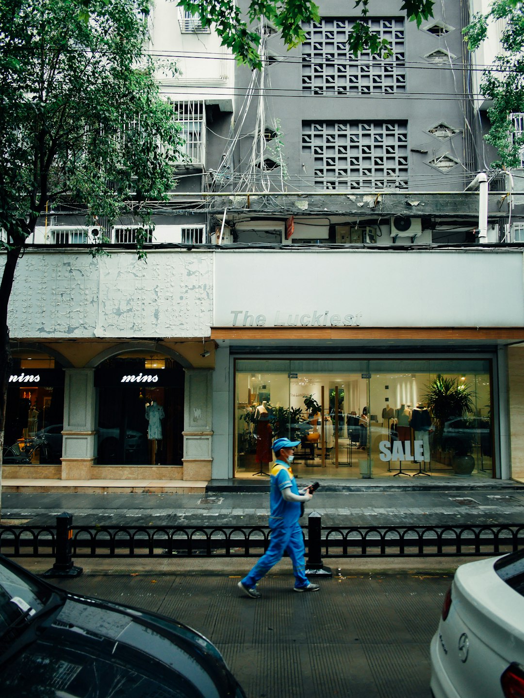 man in blue jacket walking on sidewalk near building during daytime