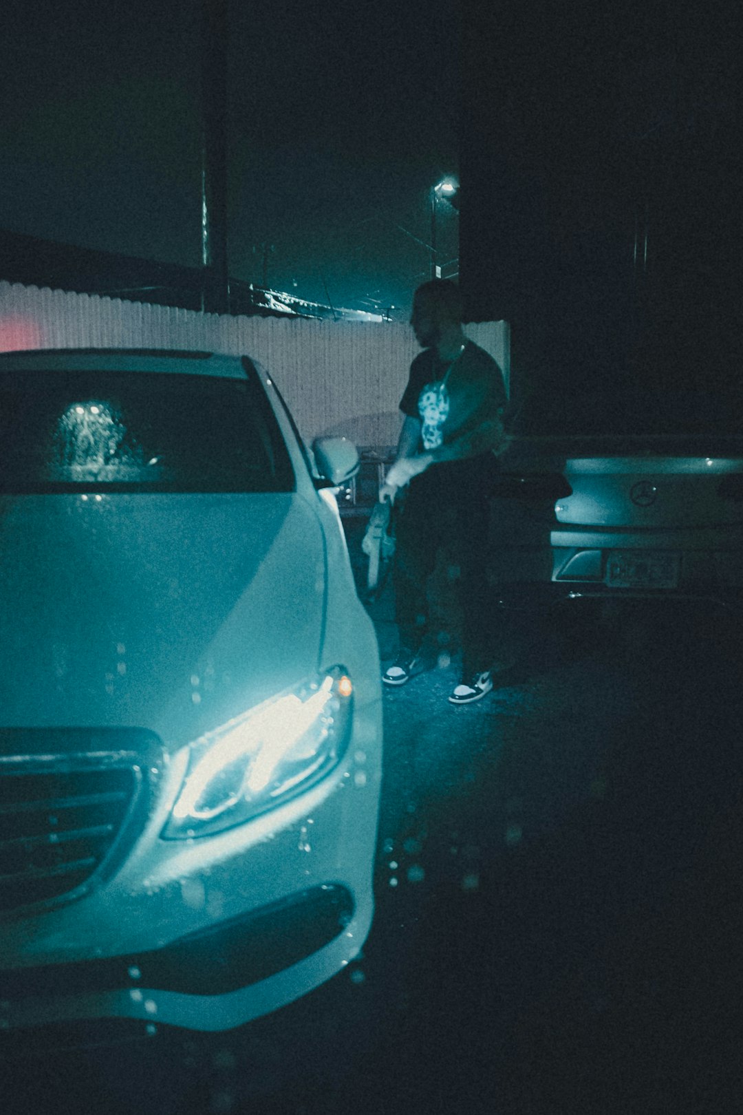 man in black jacket standing beside silver car