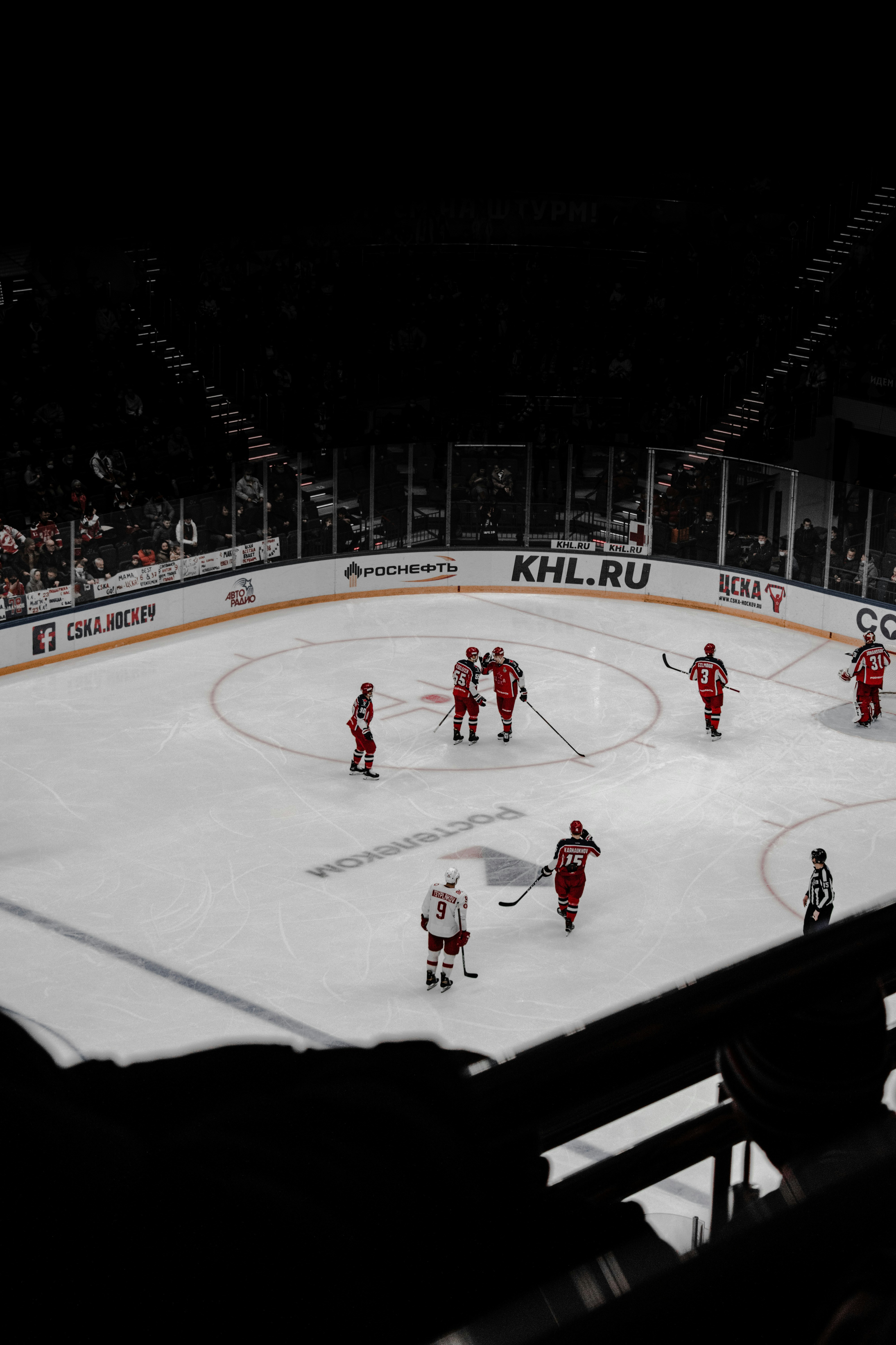 Hockey players on ice in green jerseys, dramatic arena lighting with green color wash, cold rink atmosphere