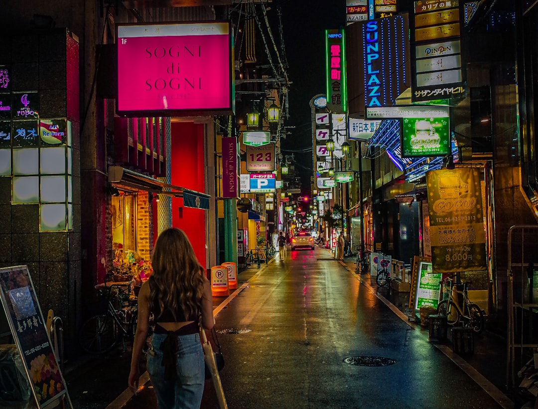 woman in brown jacket walking on sidewalk during night time