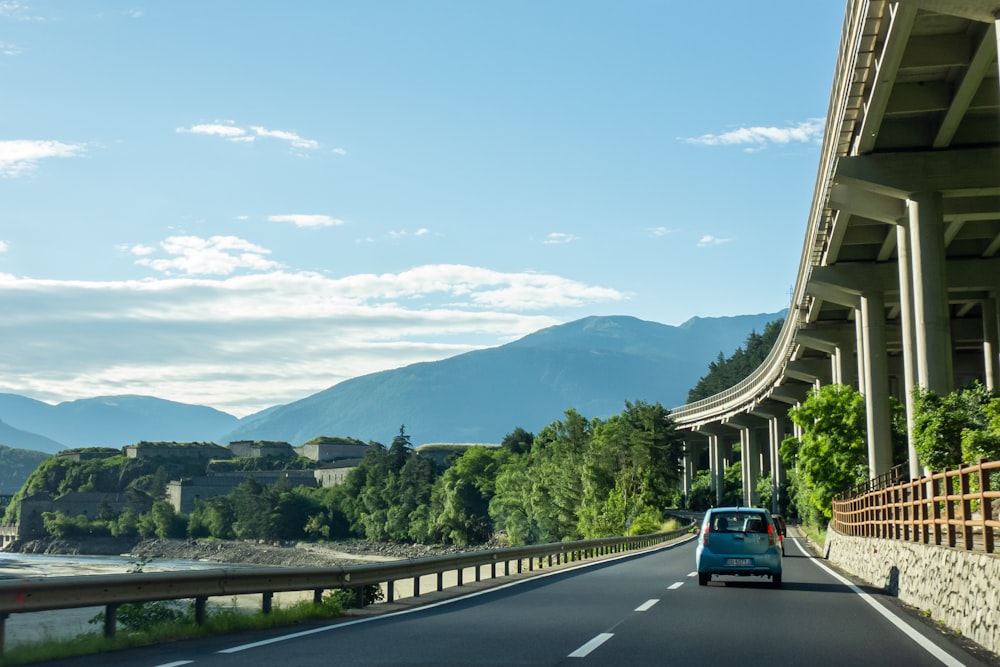 white car on road near green trees and mountains during daytime