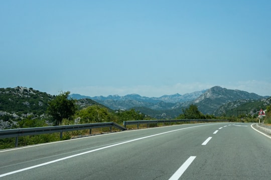 gray concrete road near green trees and mountain during daytime in Budva Montenegro