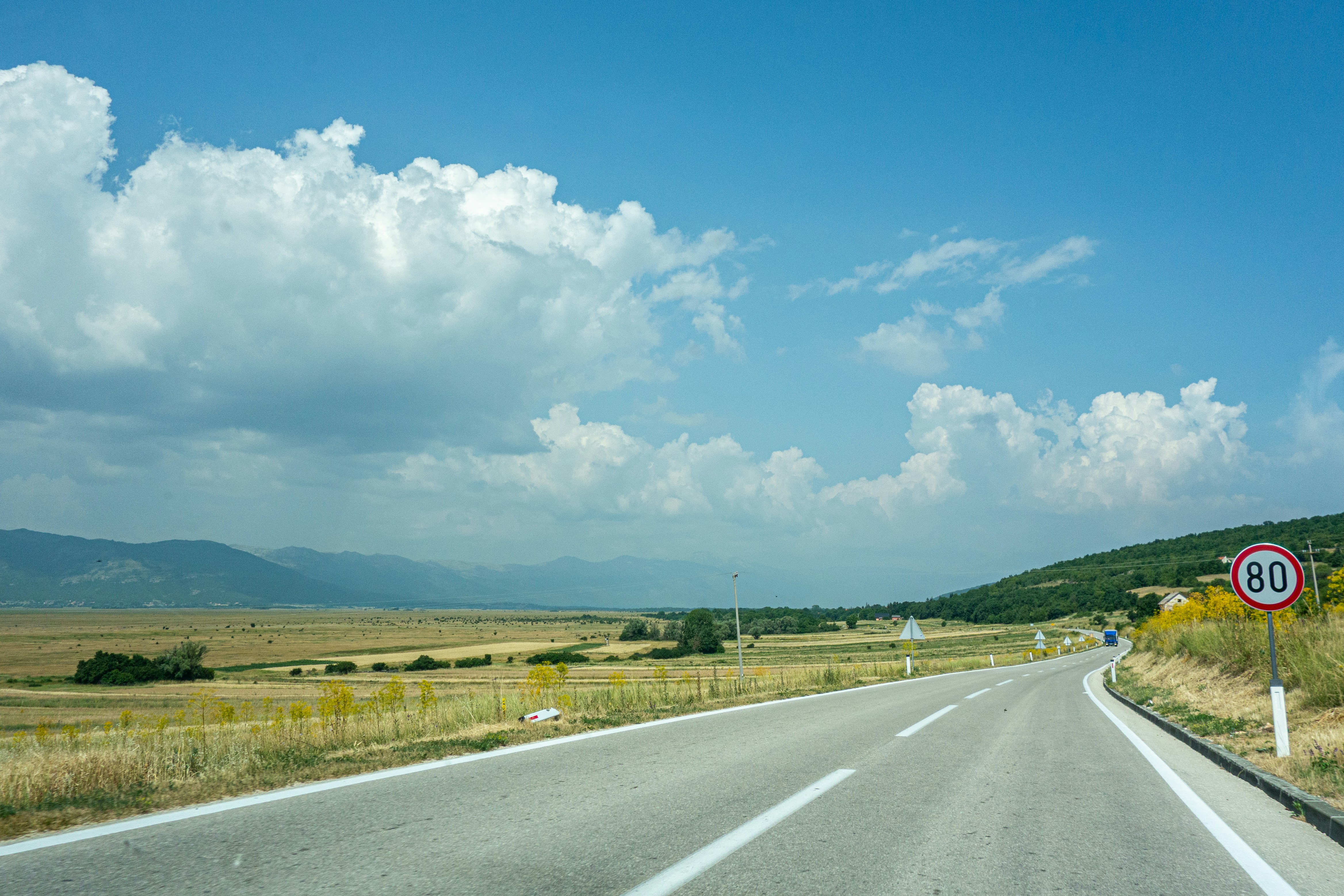 gray asphalt road under blue and white cloudy sky during daytime